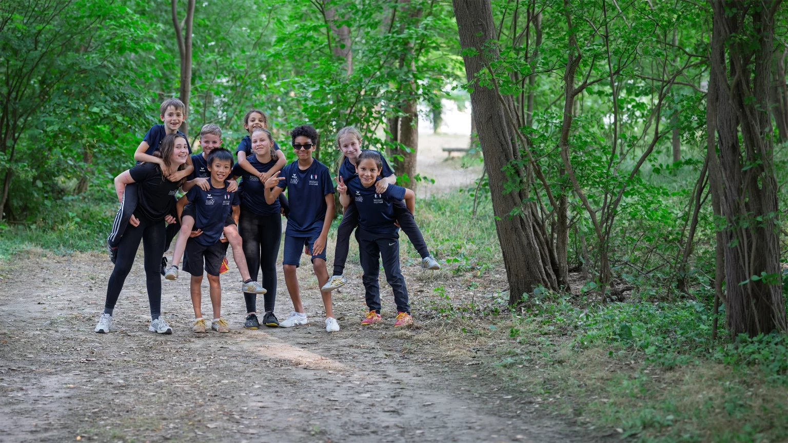 Le groupe des juniors du club, souriants et en tenue noire, sur un chemin forestier